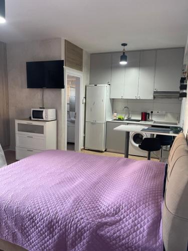 a bedroom with a purple bed and a kitchen at White Arches Modern Beautiful studio in Limassol