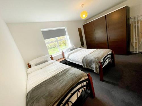 1 dormitorio con 2 camas y ventana en Majestic Homes Heathrow - FREE PARKING en Stanwell