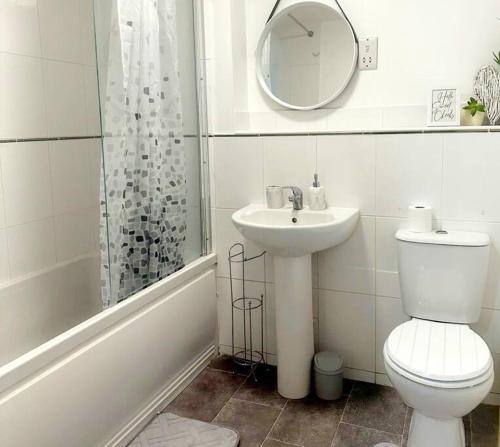 W łazience znajduje się toaleta, umywalka i lustro. w obiekcie Majestic Homes Heathrow - FREE PARKING w mieście Stanwell