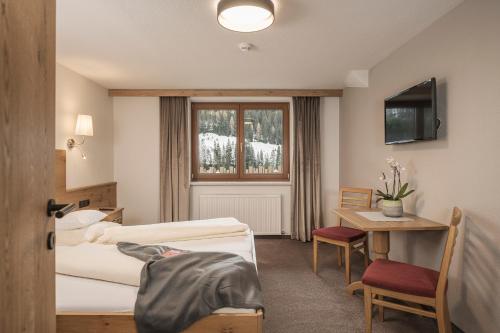 una camera d'albergo con due letti, un tavolo e una finestra di Jagdhof PURE Mountain Appartements a Tux