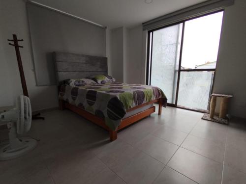 a bedroom with a bed and a large window at Apartamento a 2.5 km del parque del café in Montenegro