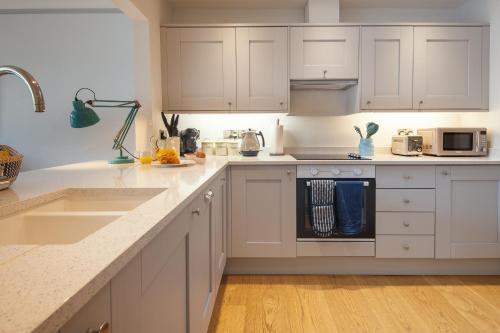 a white kitchen with white cabinets and a sink at Harbour Living in Dartmouth
