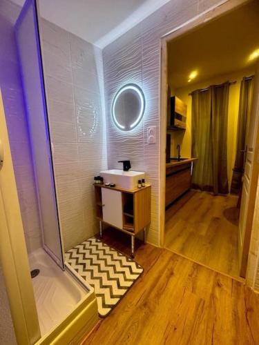 ein Badezimmer mit einer Badewanne, einem Waschbecken und einem Spiegel in der Unterkunft Chalet cosy et coconing in Meyzieu