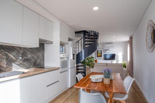 a kitchen and dining room with white cabinets and a wooden table at Apartamentos do Mercado in Covilhã