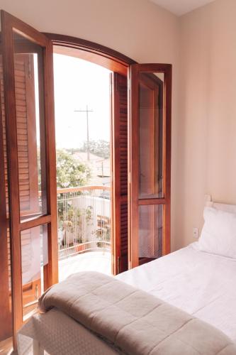 a bedroom with a bed and a large window at Hospedagem Aconchegante in Espirito Santo Do Pinhal