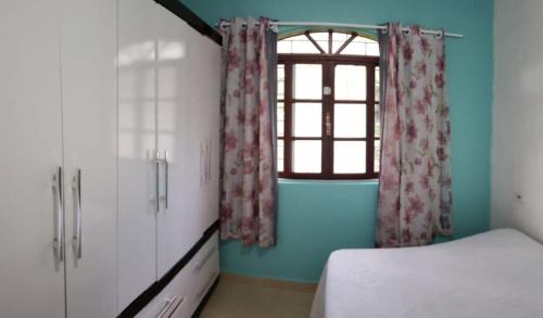 - une chambre avec un lit et une fenêtre avec des rideaux dans l'établissement Casa Vermelha Dois, à Antonina