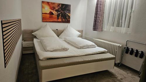 a small bedroom with a bed with white sheets and pillows at Hotel Kölner Hof in Mülheim an der Ruhr