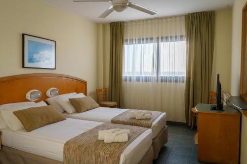 a hotel room with two beds and a television at Hostal del Sol in San Bernardo
