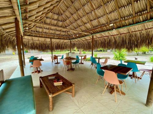a restaurant with tables and chairs under a straw roof at Hotel Las Casitas De Mar Adentro in Isla Grande