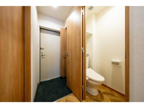 a bathroom with a toilet and a wooden door at VILLA KOSHIDO ODORI - Vacation STAY 04760v in Sapporo