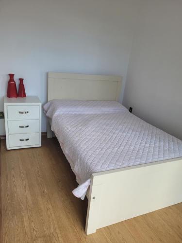 1 dormitorio con 1 cama blanca y vestidor blanco en Suíte com sala de estar, en Lages