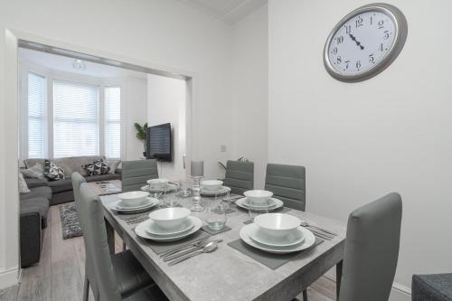 a dining room with a table and a clock on the wall at Hornsey Lodge - Anfield Apartments in Liverpool