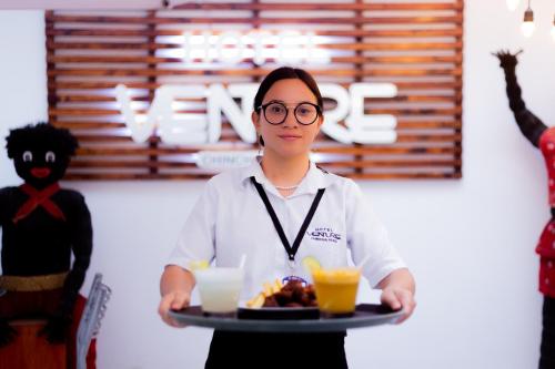 una mujer sosteniendo una bandeja de comida y bebida en Hotel Venture, en Chincha Alta