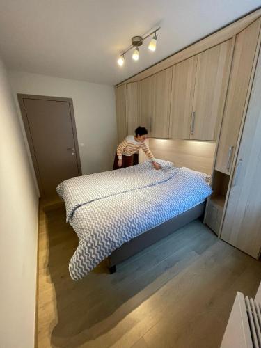a man is making a bed in a room at Vakantieappartement - Gratis garage - Topligging in Ostend