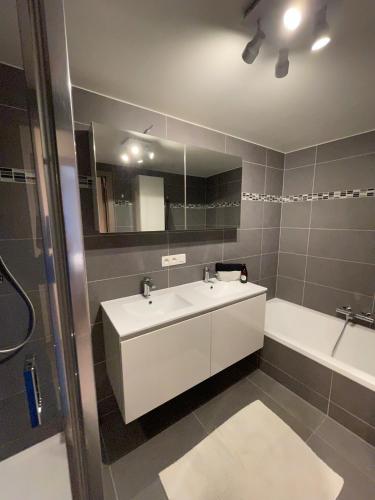 a bathroom with a sink and a tub and a mirror at Vakantieappartement - Gratis garage - Topligging in Ostend