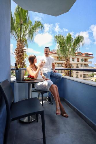a man and a woman sitting at a table on a balcony at Comfort Suites in Alanya
