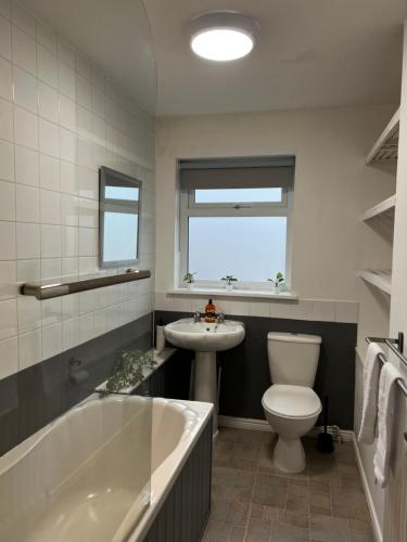 a bathroom with a tub and a toilet and a sink at Frensham House in Dallington