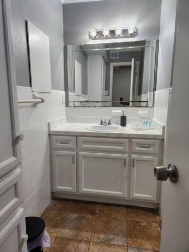 Baño blanco con lavabo y espejo en Blue Shark *E19* @ Midtown Functional 1BR King Apartment en Houston