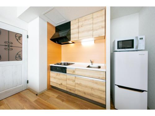 a kitchen with a white refrigerator and a microwave at VILLA KOSHIDO ODORI - Vacation STAY 04775v in Sapporo