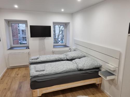 a room with two beds and a flat screen tv at City Central Apartment House in Kaiserslautern