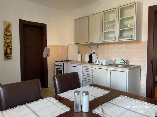uma cozinha com mesa e cadeiras e uma cozinha com armários brancos em Chalupa Liptovský domček em Liptovský Mikuláš