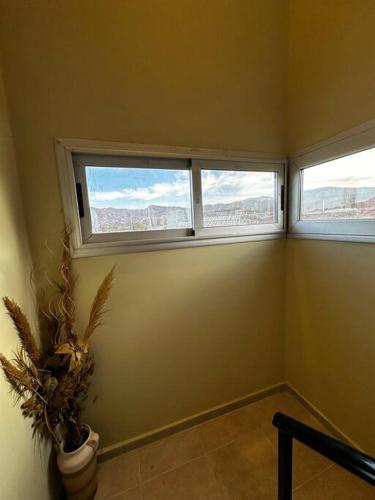 a room with two windows and a potted plant at Villamagna, casa en Potrerillos in Potrerillos