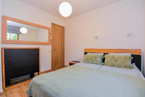 a bedroom with a large bed and a television at Apartamentai Gėlių Vila in Nida