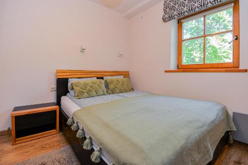 a bedroom with a bed and a window at Apartamentai Gėlių Vila in Nida