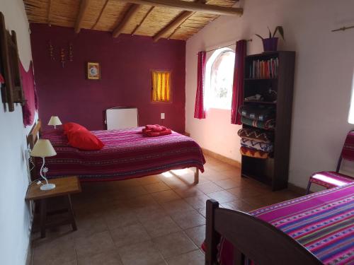 um quarto com uma cama com almofadas vermelhas em Cabaña El Cardón,casita en el campo quebradeño em Humahuaca