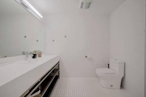 a white bathroom with a toilet and a sink at KCM Tremont Oaks Apartments 1 in Cleveland