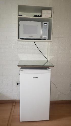 a microwave sitting on top of a refrigerator at Paz e Amor Suite in Abraão