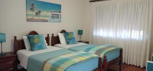 a bedroom with two beds and a painting on the wall at A Casa da Ti Laura - AL in Aveiro