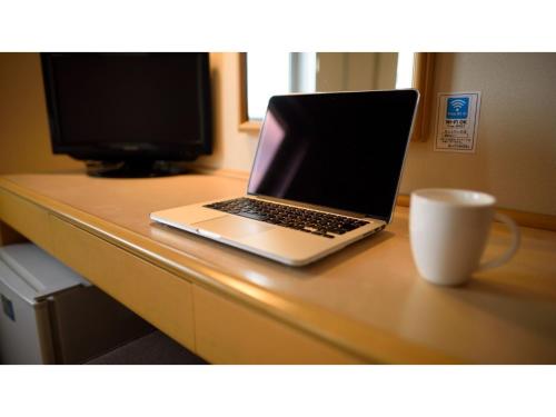a laptop computer sitting on top of a desk with a cup at Green Hotel Kitakami - Vacation STAY 09805v in Kitakami