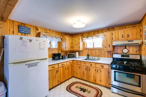 a kitchen with wooden cabinets and a white refrigerator at Cozy Chemo Pond Cabin with Dock and Waterfront Views in Eddington