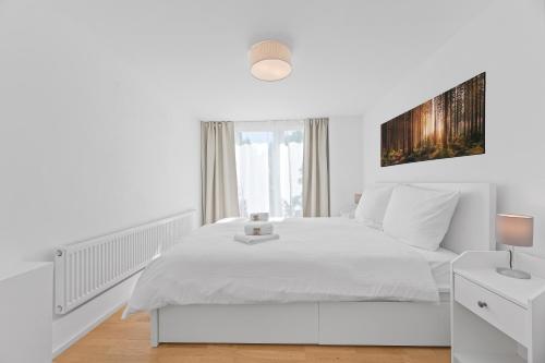 ein weißes Schlafzimmer mit einem weißen Bett und einem Fenster in der Unterkunft FEEL HOME Apartments in Schönaich