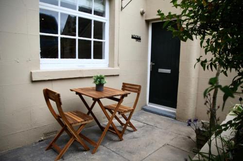 a table and two chairs sitting next to a door at Molokai Snug Best location North South bay Courtyard garden Parking in Scarborough