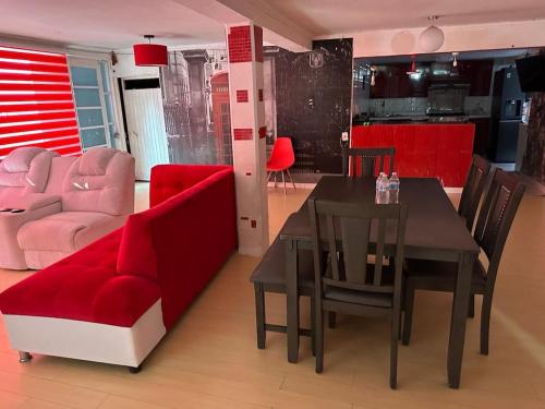 a living room with a red couch and a table and chairs at Casa Vázquez , "Como en casa" , hospédate con nosotros y recibirás una atención personalizada, servicio y confort nos distingue. in Pachuca de Soto