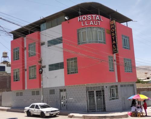 un edificio rojo y blanco con un coche aparcado delante en HOSTAL LLAUT * *, en Moquegua