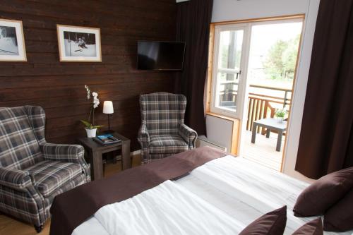 a bedroom with a bed and two chairs and a balcony at Eriksgårdens Fjällhotell in Funäsdalen