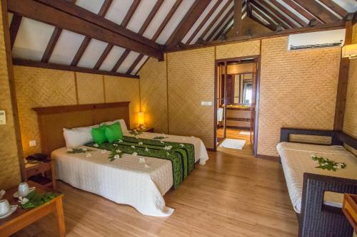 a bedroom with a bed with green pillows in it at Maitai Rangiroa in Avatoru