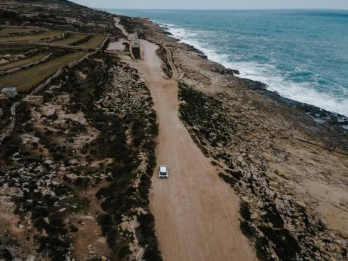 a car driving down a dirt road next to the ocean at SeaWaves Apartments in Xgħajra