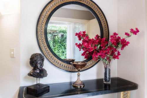 a mirror on a shelf with flowers and a bust at Sanctuary Palms in Paihia