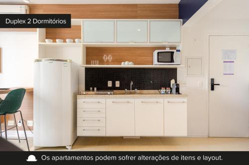 a kitchen with white cabinets and a refrigerator at Charlie NYC Berrini in Sao Paulo