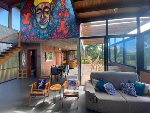 Luxury Holiday Home In Ibiraquera-SC في إيمبيتوبا: غرفة معيشة مع أريكة وجدارية ملونة