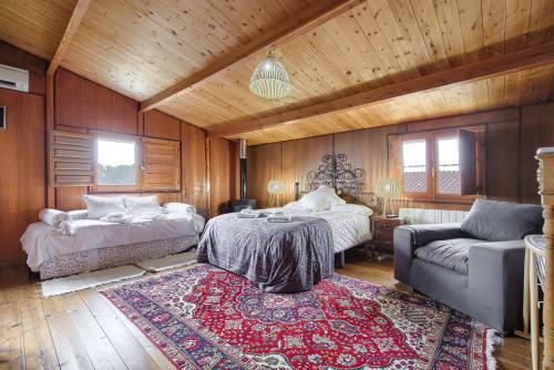 Habitación con 2 camas, sofá y alfombra. en La Cabaña en Valdemorillo