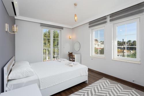 a white bedroom with two beds and windows at Villa Capital in Dalyan