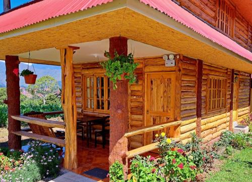 Cabaña de madera con mesa y techo rojo en Fundo Hassinger, en Oxapampa