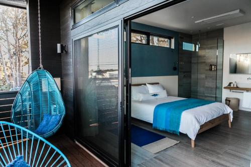恩西尼塔斯的住宿－Twelve Senses Retreat, a Member of Design Hotels，卧室设有秋千床和玻璃窗。