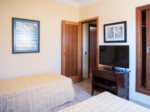 a bedroom with two beds and a flat screen tv at Caleta de Fuste Villa Vergel with Huge Private Pool, Jacuzzi, & BBQ by Amazzzing Travel in Caleta De Fuste