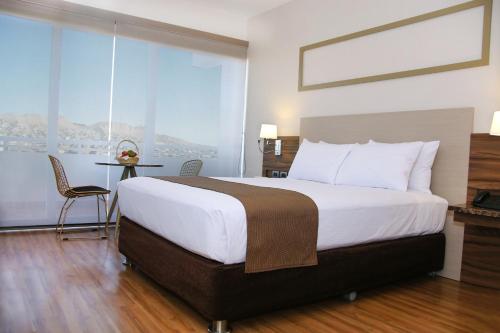 a large bed in a hotel room with a large window at DM Hoteles Moquegua in Moquegua